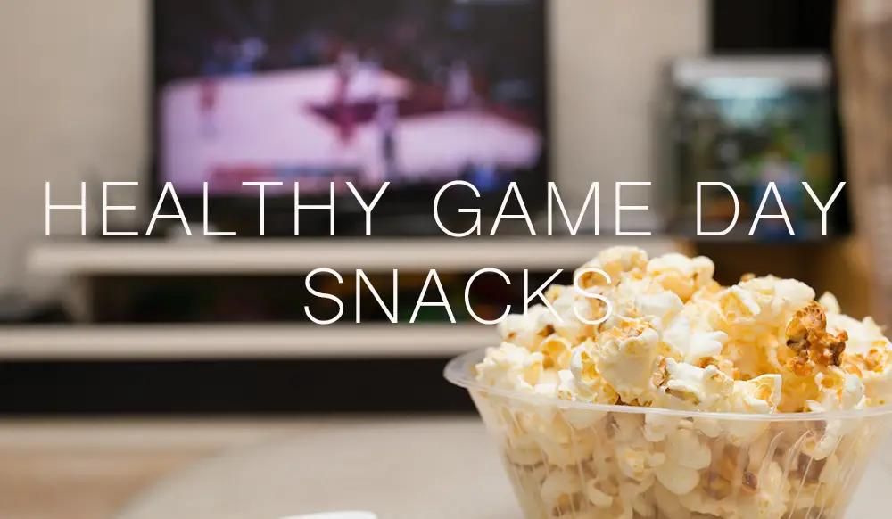 popcorn and remote control on sofa with a TV broadcasting basketball match on background