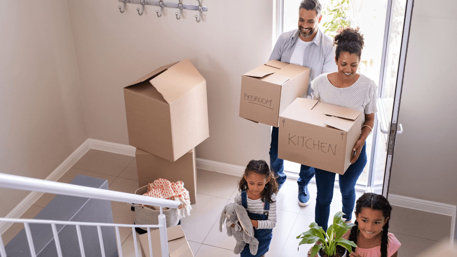 Family carrying moving boxes moving into a new home