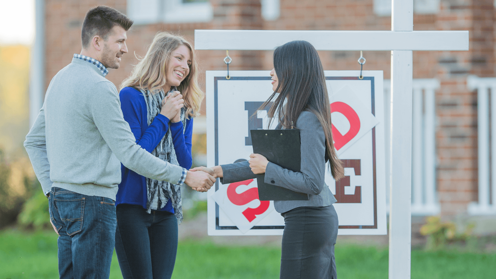 Couple buying a new house with a realtor out front