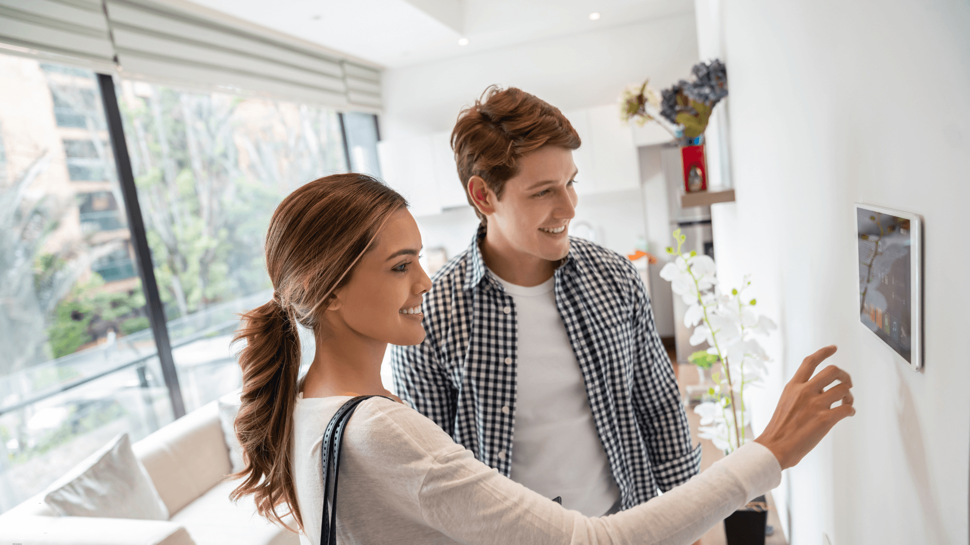 Couple looking at their home security system panel on the wall 