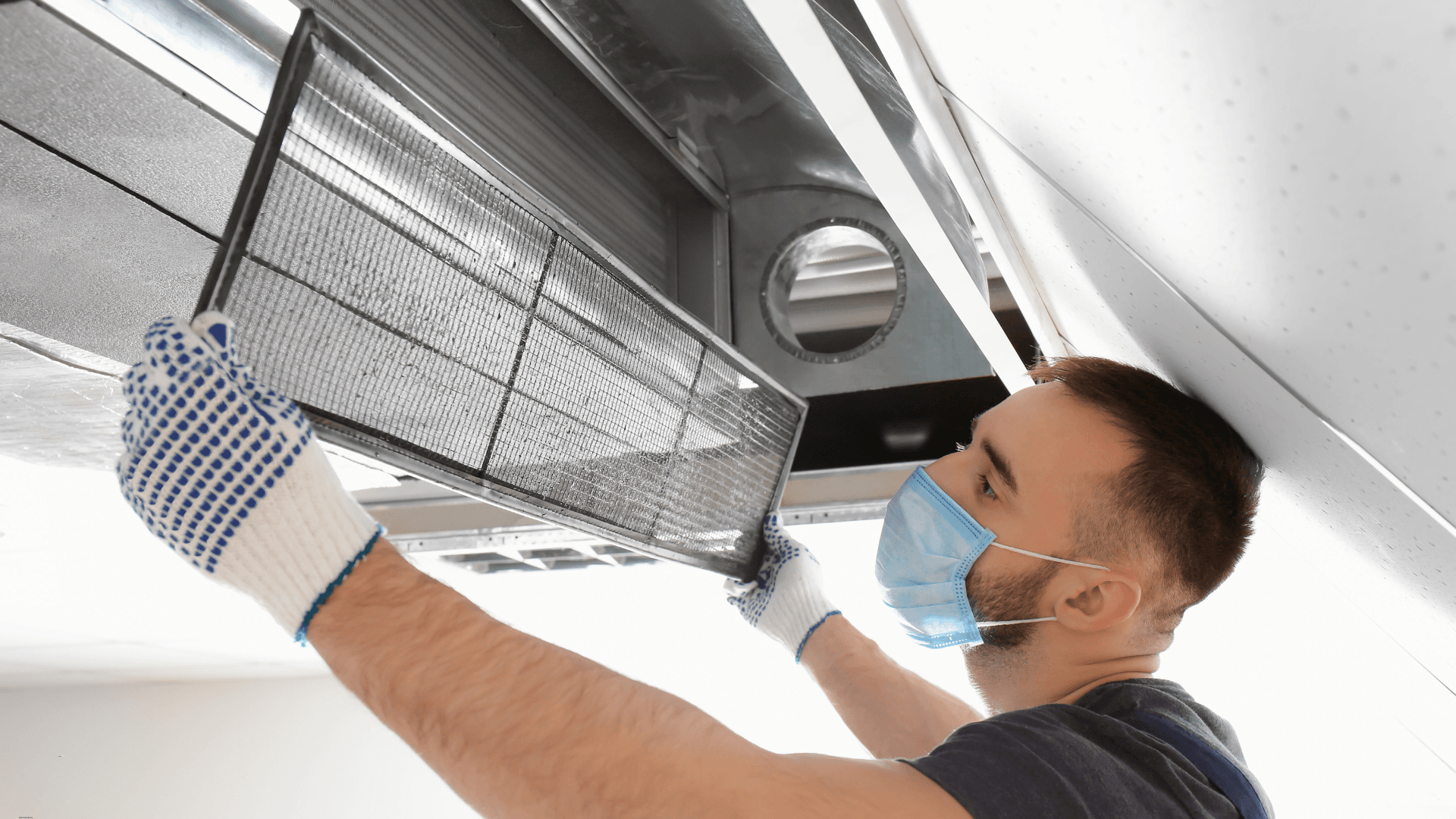 Man installing a new HVAC filter with a mask on